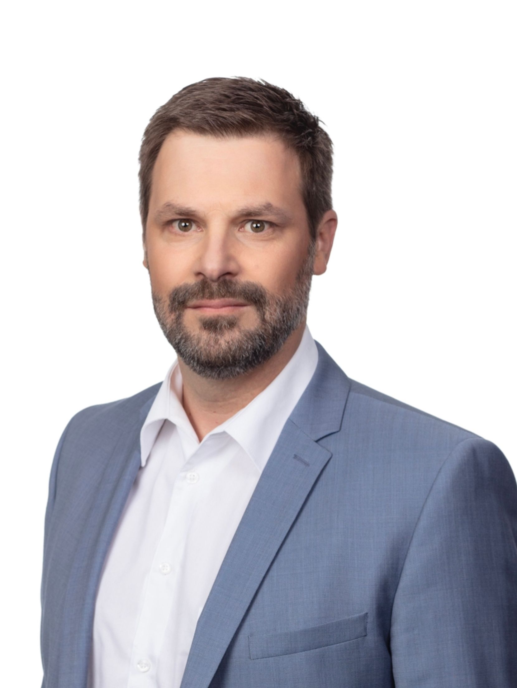 Mann mit Bart, Anzug und weissem Hemd schaut in die Kamera.
